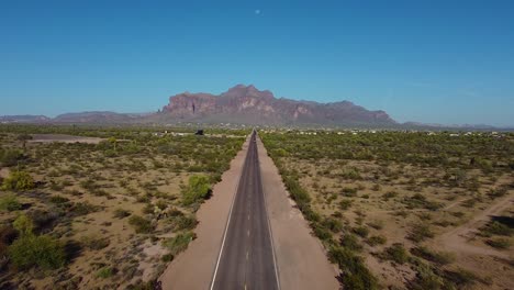 Long-desert-highway-leading-straight-to-mountains-in-hot-arid-Southwestern-landscape