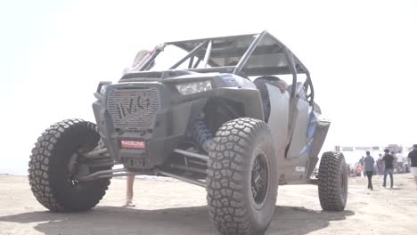 Man-and-blonde-woman-riding-a-rally-buggy-car-in-rally-raid-race