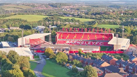 Barnsley-football-club-stadium-seats,-bright-red-and-yellow-against-forested-landscape