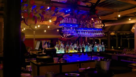 Gimbal-dolly-of-bar-with-bottles-and-nice-decorative-lights,-bartender-working