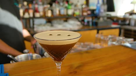 Slow-orbit-of-classic-Kahlua-espresso-on-bar-top,-bartender-working-in-background