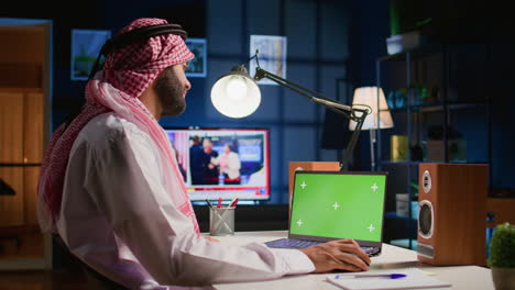 Man-scrolls-on-green-screen-laptop