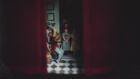 A-Group-Family-of-Small-Glass-Porcelain-Doll-Figures-figurines-Inside-a-Dark-Moody-Hand-Painted-Antique-Vintage-Red-Curtain-House-In-Shadow-Miniature