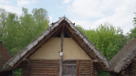 Ancient-Wooden-Slavic-House-with-a-skull---Biskupin,-Poland---tilt-down-shot