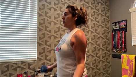 Hispanic-woman-working-out-with-dumbbells-in-home-gym,-doing-upper-body-exercise
