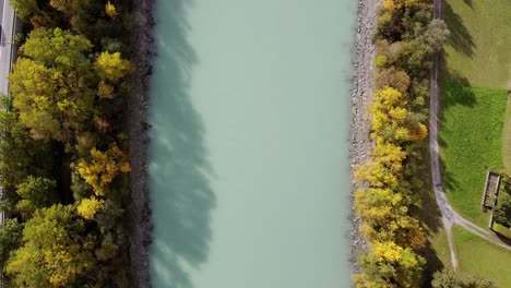 Aerial-to-down-flying-over-river-with-trees-growing-around-on-a-sunny-day