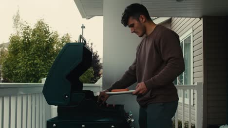 A-young-man-is-grilling-delicious-hot-dogs-on-the-porch-of-his-house