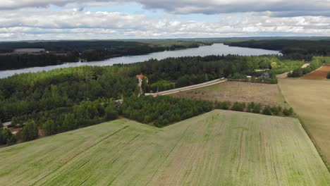 Panoramic-Aerial-view-of-crop-fields-and-a-lake-in-rural-area-of-Borowy-Młyn-in-Kaszuby,-Pomorskie,-Poland