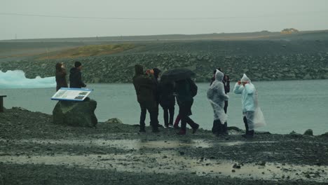 Tourists-in-rain-ponchos-standing-at-Lake-Jokulsarlon-in-Iceland