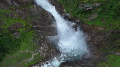 Wunderschöne-Filmische-Aufnahmen-Eines-Wasserfalls-Auf-Einem-Mit-Felsen-Und-Gras-Bedeckten-Berg