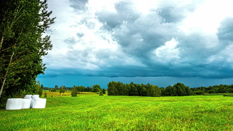 Timelapse-shot-of-dark-rain-clouds-flying-over-green-grasslands-at-daytime
