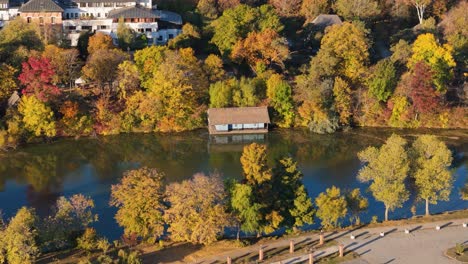 Cinematic-Aerial-View-Of-A-Small-House-On-Lake-Herastrau-In-Bucharest,-Romania,-Autumn