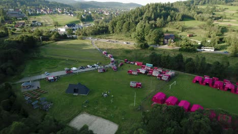 4k-Aerial-View-of-Firefighter's-Picnic,-Fire-Trucks,-Tents-and-People-during-Sunrise