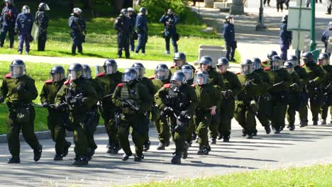 Eine-Gruppe-Von-Bereitschaftspolizisten-In-Voller-Taktischer-Schutzausrüstung-Und-Helmen-Rennt-Vor-Beginn-Des-G7-Gipfels-In-Québec,-Kanada,-Eine-Straße-Hinauf