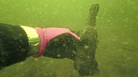 Underwater-View-of-Severely-Polluted-Water-with-Diver's-Hand-Holding-Dirty-Bottle