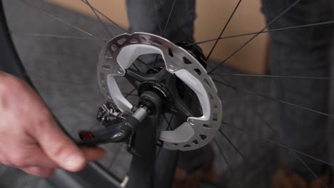 Male-hand-of-bicycle-mechanic-tightening-wheel-on-bicycle-fork-with-disc-brakes-using-lever-on-thru-axle-bolt