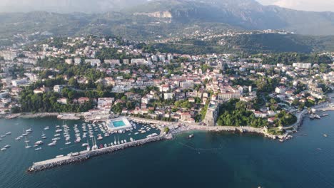 Herceg-Novi-coastal-town-below-Mount-Orjen-and-on-Adriatic-coast,-aerial
