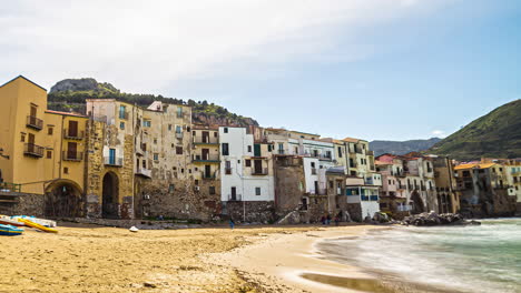 A-Chain-Of-Old-Buildings-At-A-Shore-With-Mountains-In-The-Background-In-Sicily