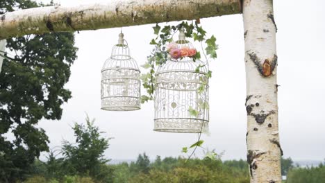 Beautiful-wedding-birch-arch-bird-cage-decoration-with-flowers-in-cloudy-park