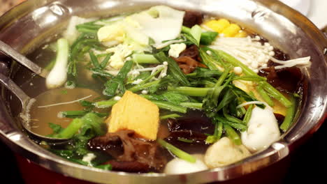 Caldo-De-Pollo-Hirviendo-Cargado-Con-Tofu,-Verduras,-Champiñones,-Especias-Y-Aromatizado-Con-Un-Distintivo-Condimento-Tailandés-Dentro-De-Un-Restaurante-En-Bangkok,-Tailandia