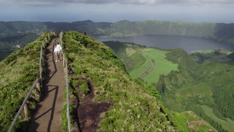 Woman-exploring-Miradouro-da-Grota-do-Inferno,-Azores-with-lagoon-view
