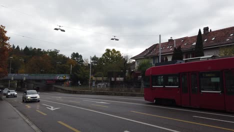 A-Red-Tram-Train-Wagon-Rides-the-Streets-of-Bumpliz-Bern-Switzerland-in-Autumn
