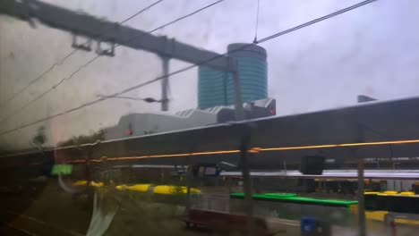 POV-through-rainy-train-window-arriving-at-Utrecht-Central-station