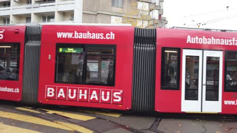 A-red-tram-car-travels-through-the-streets-of-Bern,-Switzerland-in-autumn