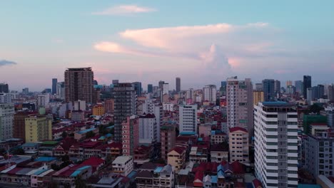 Luftaufnahme-Einer-Drohne,-Die-Nach-Links-Schwenkt-Und-Auf-Die-Hauptstadt-Kambodschas,-Phnom-Penh,-Blickt,-Während-Die-Sonne-Untergeht