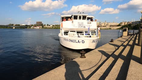 Ausflugsboot-Legt-Am-Ottawa-River-An,-Mit-Stadtbild-Im-Hintergrund,-Kanada