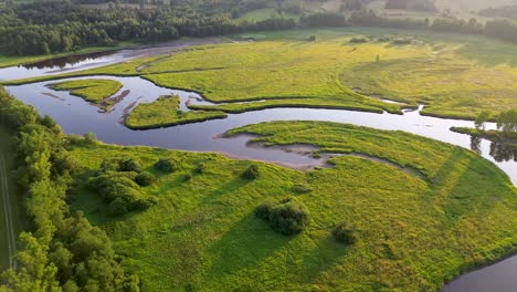 cinematic-view-from-a-drone,-while-rotating-over-a-wide-river-that-flows-through-green-nature