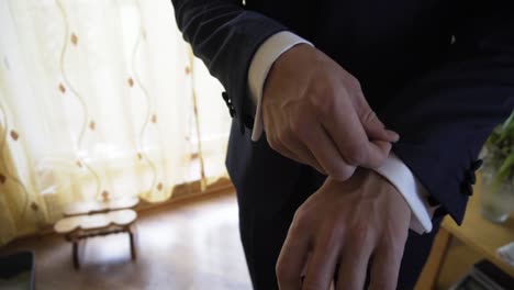 Close-up-of-wedding-groom-slowly-adjusting-his-dark-suit-with-hands