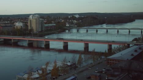 Bridge-in-downtown-Umeå,-Sweden,-on-a-cold-autumn-morning-with-layer-of-ice-on-the-river,-seen-from-hotel-window