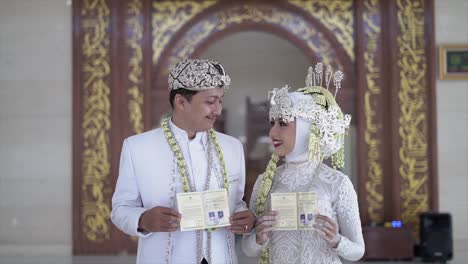 Bride-and-Groom-holding-buku-nikah-or-open-the-marriage-book-at-wedding-procession