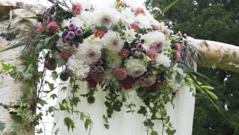 Hochzeitsdekoration-Mit-Gemischten-Blumen,-Langsame-Nahaufnahme,-Pfanne-Auf-Birkenbogen-Mit-Baum-Im-Hintergrund
