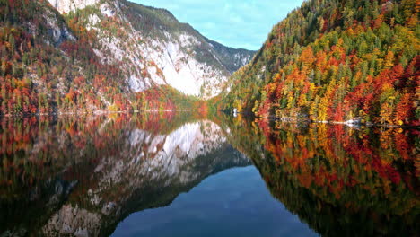 Slowly-panning-out-shot-of-a-lake-with-calm-water-reflecting-the-mirror-image-of-forest-and-mountains-above-it