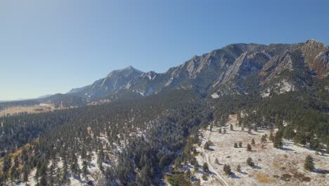 Aerial-Drone-shot-of-the-flatiron-mountains-covered-in-snow-in-Boulder,-Colorado,-USA-on-a-fall-day