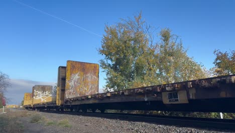 An-empty-freight-train-goes-over-railroad-tracks-on-a-blue-sky-day
