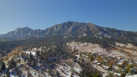 Drone-flying-towards-the-flatirons-In-Boulder,-Colorado,-USA-on-a-clear-fall-day-with-light-snow
