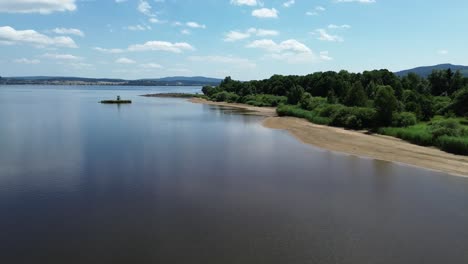 cinematic-view-from-a-drone-flying-over-a-sandy-beach-on-the-shore-of-a-big-blue-lake