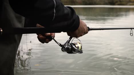 Close-Up-Fisherman-Winding-Reel-Reeling-In-Fishing-Rod-super-slow-motion