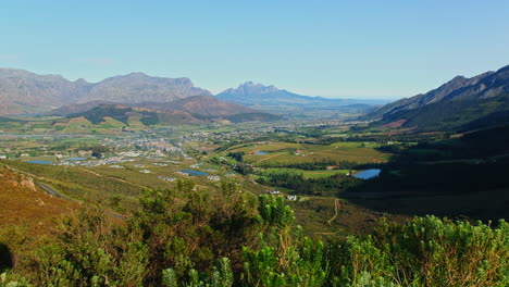 Picturesque-Franschhoek-valley-nestled-between-towering-mountains,-high-angle