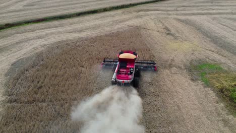 farm-combine-harvesting-soybeans-on-a-midwestern-farm-field,-aerial-drone