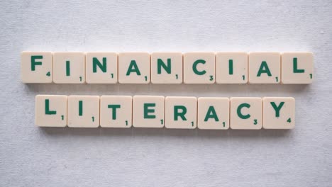 Hand-forming-phrase-"financial-literacy"-with-green-letters
