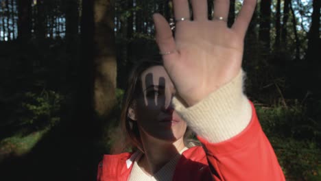 Woman-holding-her-hand-over-sunlight-in-forest