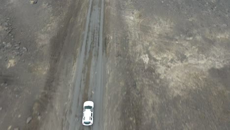Aerial-drone-shot-following-a-car-driving-off-road-in-Iceland.--Vertical-view