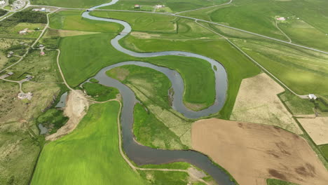 Winding-river-in-grasslands-green-field-aerial-shot-Iceland