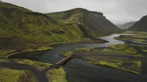 Río-Con-Un-Puente-En-La-Naturaleza-Salvaje-Y-Cruda-En-Toma-Aérea-De-Islandia