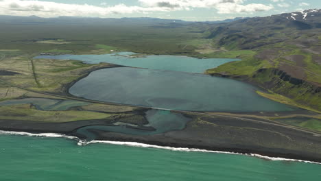 Bridge-crossing-a-pond-along-the-sea-aerial-shot-Iceland
