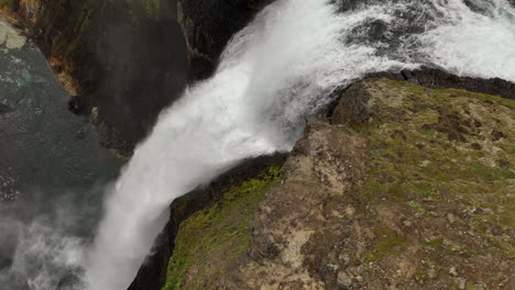 Wasser-Fließt-Auf-Einem-Riesigen-Felsen-Vom-Wasserfall-Haifoss-In-Zeitlupe-Aus-Der-Luft